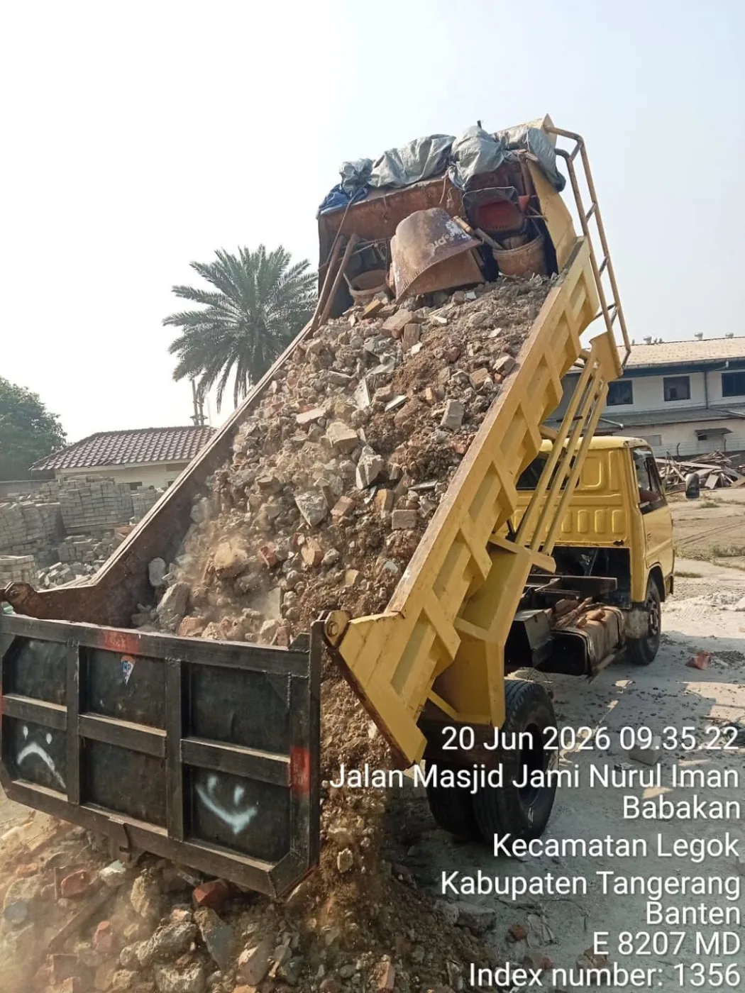 Dump truck menurunkan muatan puing campuran di lokasi pembuangan